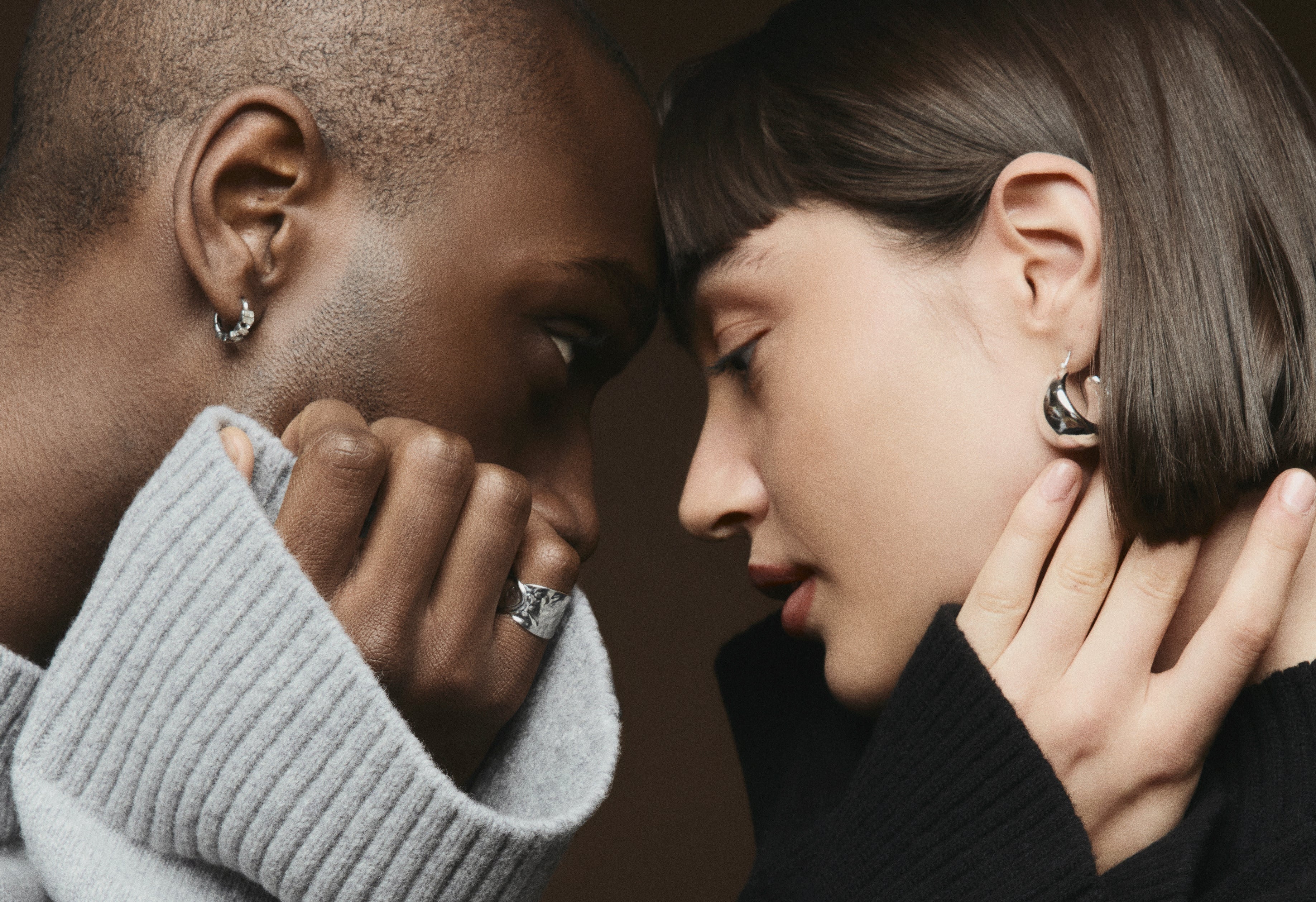 Two people facing each other with a warm brown background